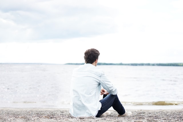 man sitting and thinking on a beach