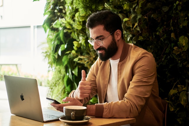 man working on a computer giving a thumbs up