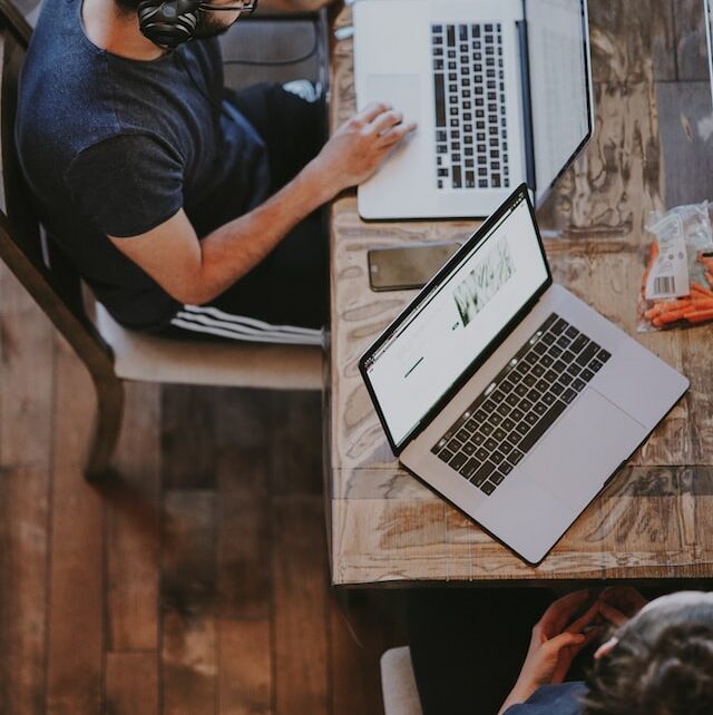 man wearing headphones sitting and operating a laptop